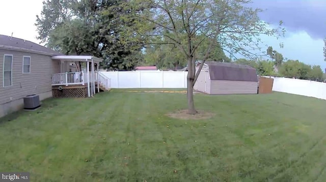 view of yard featuring a fenced backyard, a storage unit, and an outbuilding