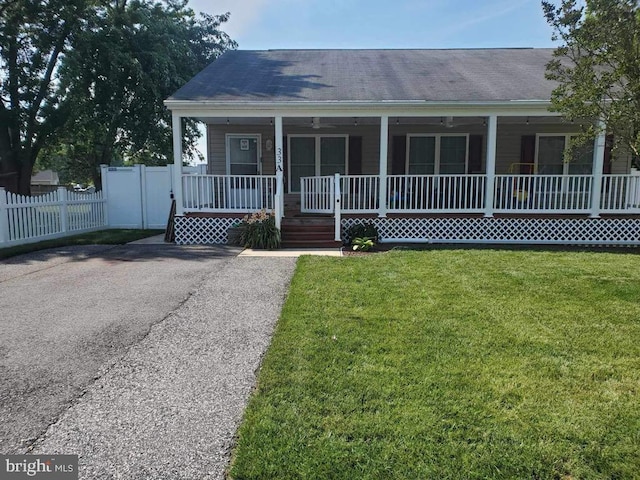 view of front facade featuring a front yard, covered porch, fence, and driveway