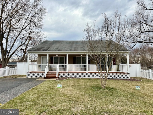 view of front facade with a porch, a front lawn, fence, and aphalt driveway