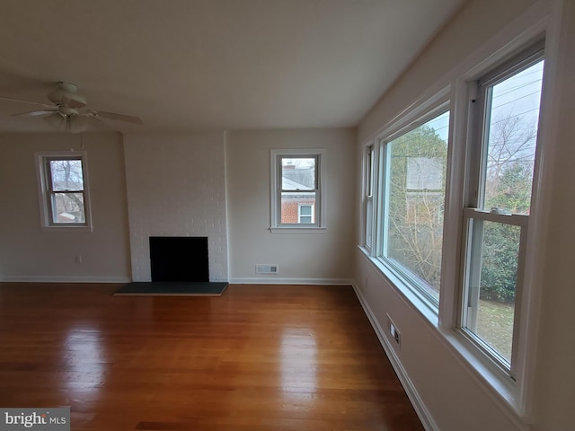 unfurnished living room featuring plenty of natural light, dark wood-type flooring, and a fireplace