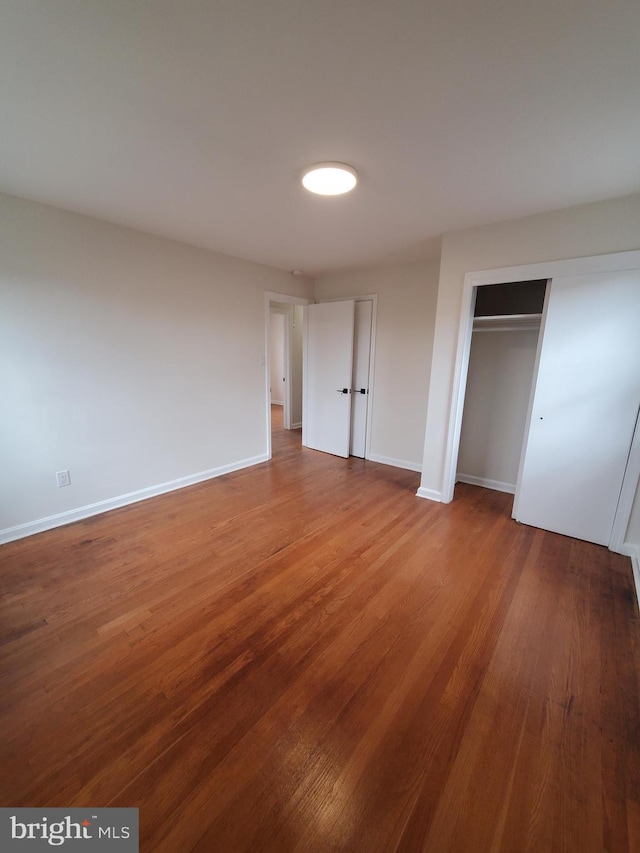 unfurnished bedroom featuring wood-type flooring and a closet