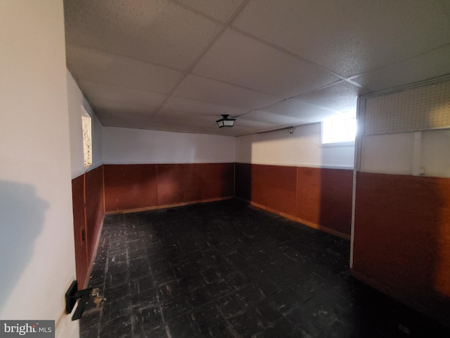 spare room with a drop ceiling and wooden walls