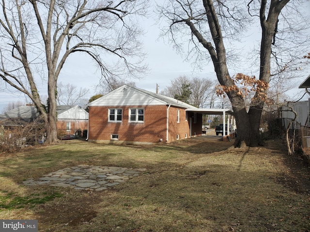 rear view of property featuring a lawn and a carport