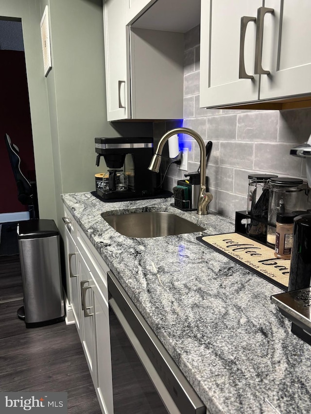 kitchen featuring beverage cooler, dark wood finished floors, light stone counters, a sink, and backsplash