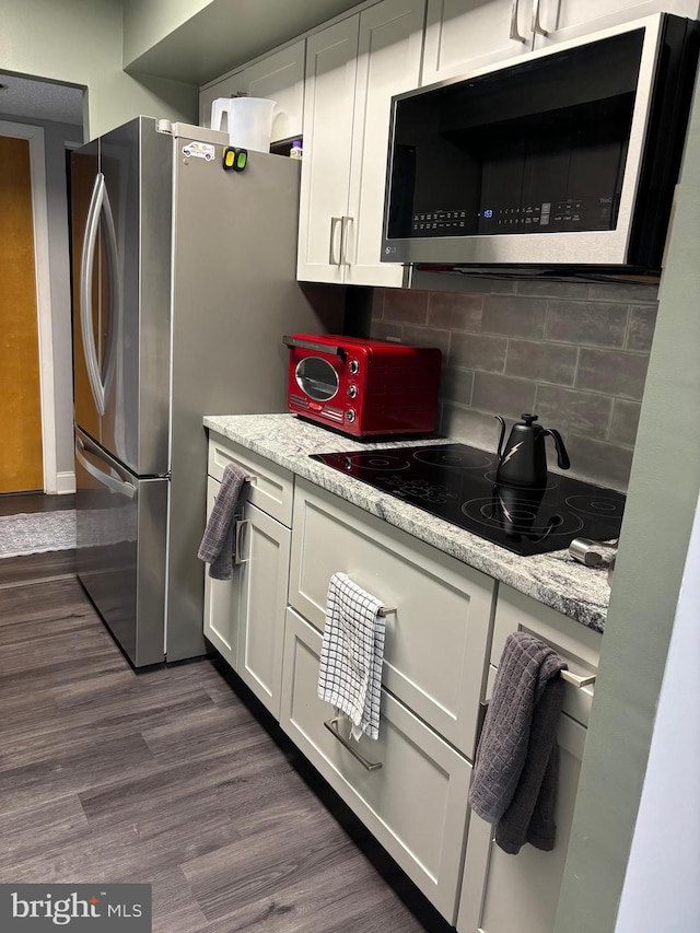 kitchen with white cabinetry, stainless steel microwave, dark wood finished floors, and black electric cooktop