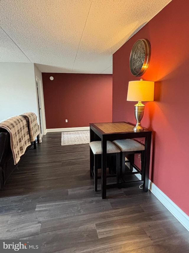 dining area with a textured ceiling, baseboards, and wood finished floors