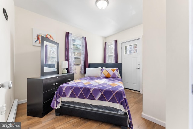 bedroom featuring a baseboard heating unit and light hardwood / wood-style flooring