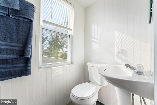 bathroom featuring sink, tile walls, and toilet