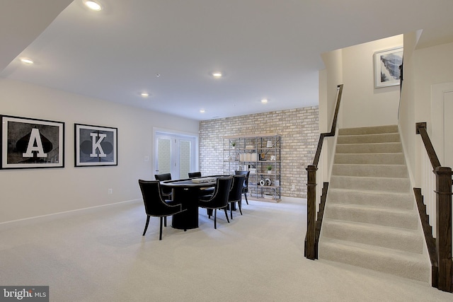 carpeted dining space featuring brick wall