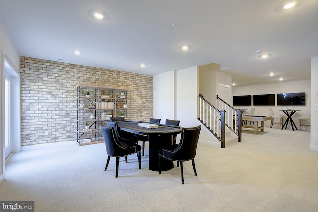 carpeted dining room with brick wall