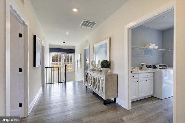 hall with sink, separate washer and dryer, and light hardwood / wood-style floors