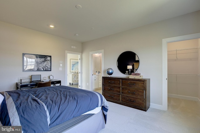 carpeted bedroom featuring a spacious closet and ensuite bath