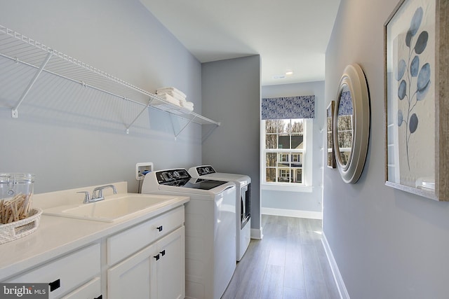 washroom with separate washer and dryer, sink, and light hardwood / wood-style flooring