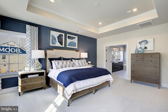 bedroom with light carpet, a tray ceiling, crown molding, and ensuite bathroom