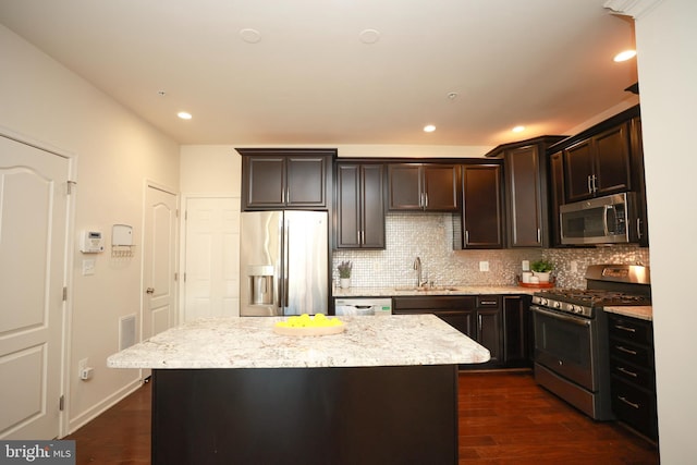 kitchen featuring light stone counters, appliances with stainless steel finishes, a center island, and sink