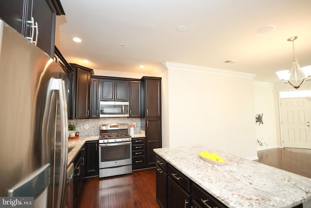 kitchen featuring dark hardwood / wood-style floors, backsplash, hanging light fixtures, ornamental molding, and stainless steel appliances