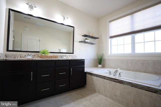 bathroom with tiled tub, vanity, and tile patterned floors