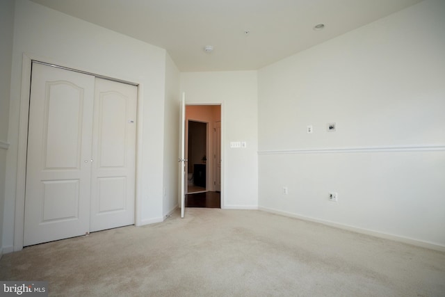 unfurnished bedroom with light carpet and a closet