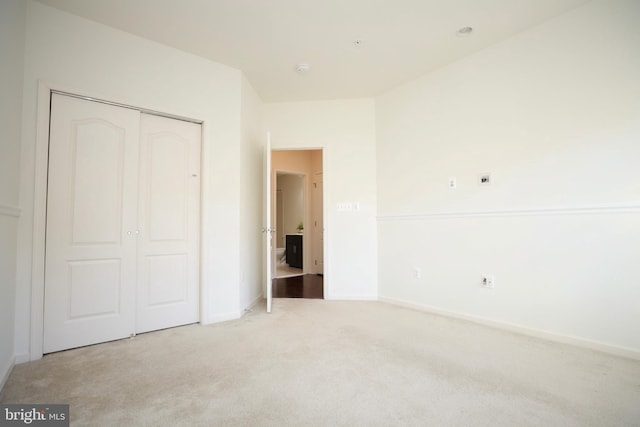 unfurnished bedroom featuring light carpet and a closet