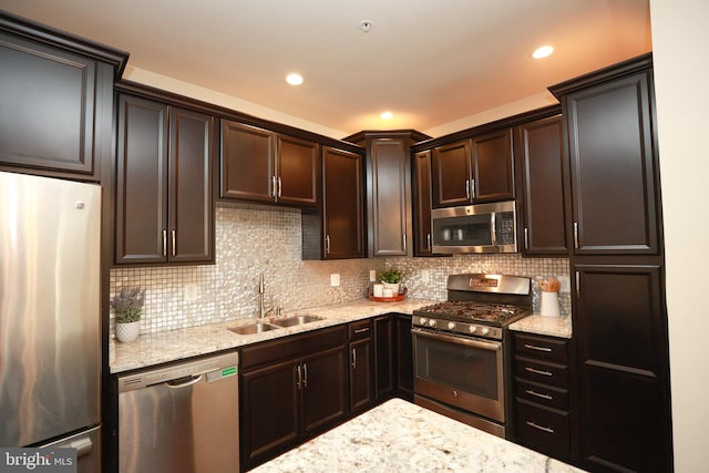 kitchen with stainless steel appliances, light stone countertops, sink, and decorative backsplash