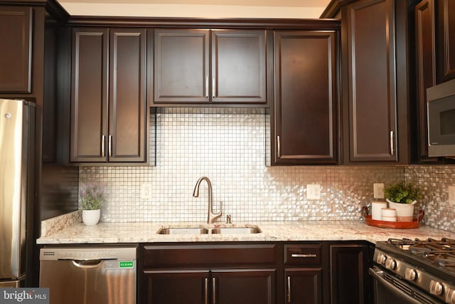 kitchen with sink, appliances with stainless steel finishes, backsplash, dark brown cabinetry, and light stone countertops