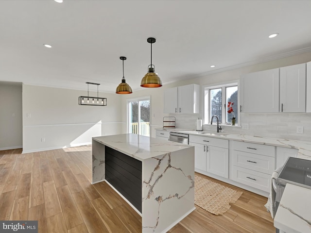 kitchen with sink, white cabinetry, a center island, hanging light fixtures, and stainless steel appliances