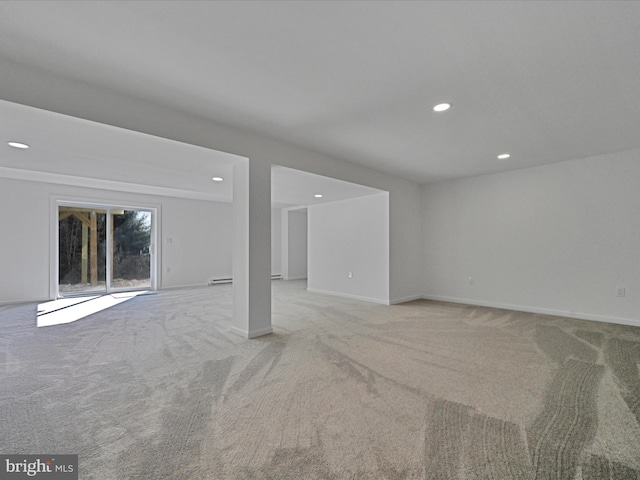 spare room featuring baseboard heating and light colored carpet