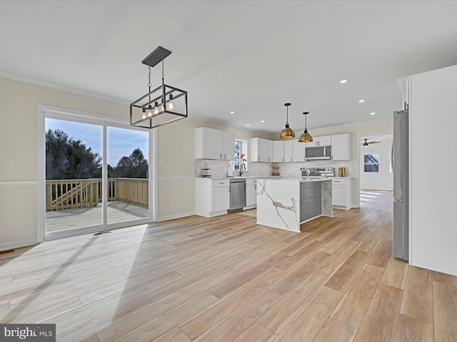 kitchen with white cabinetry, tasteful backsplash, a center island, hanging light fixtures, and stainless steel appliances