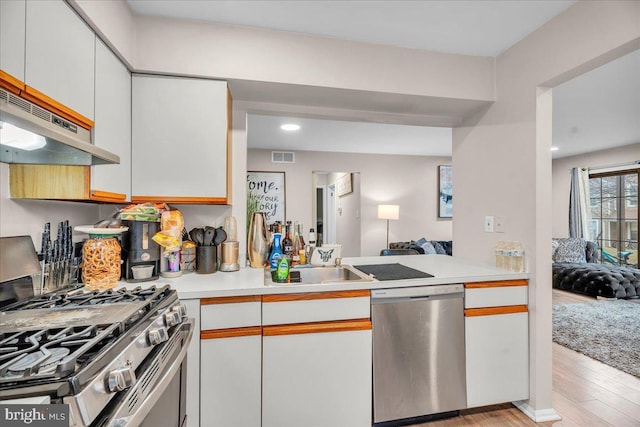 kitchen featuring sink, white cabinetry, light hardwood / wood-style flooring, kitchen peninsula, and stainless steel appliances