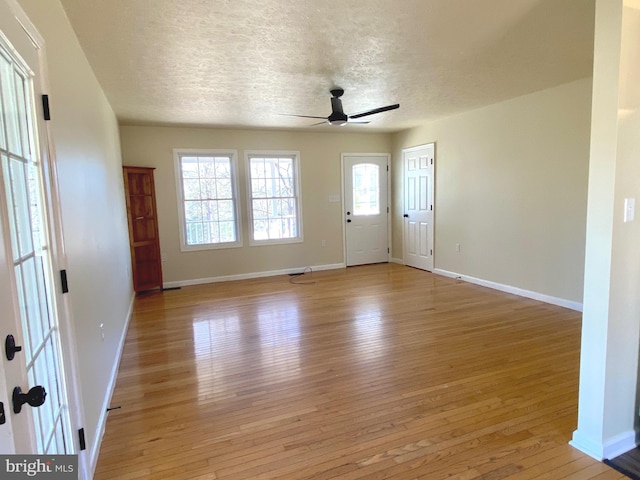 foyer entrance with ceiling fan, a textured ceiling, and light hardwood / wood-style flooring