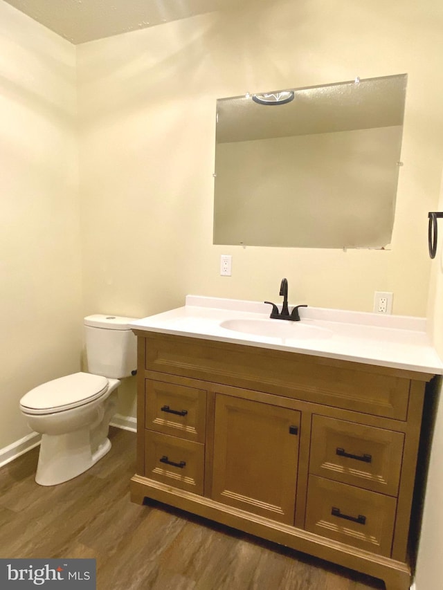 bathroom with hardwood / wood-style flooring, vanity, and toilet