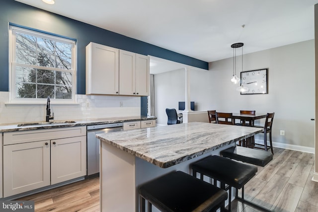 kitchen featuring sink, decorative light fixtures, a center island, a kitchen breakfast bar, and dishwasher