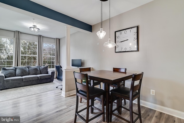 dining area with hardwood / wood-style flooring, beam ceiling, and ornate columns