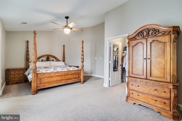 bedroom with ceiling fan, light carpet, and a walk in closet