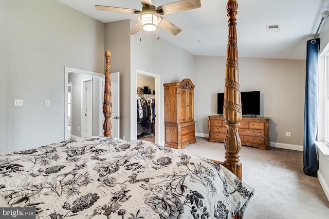 carpeted bedroom featuring lofted ceiling, a walk in closet, a closet, and ceiling fan