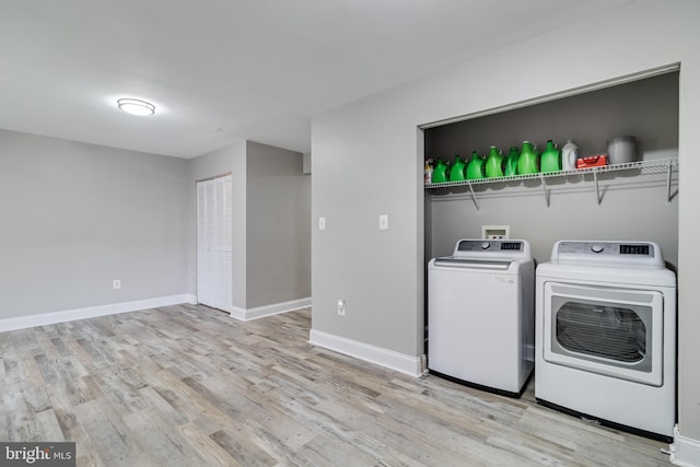 laundry area with washer and clothes dryer and light wood-type flooring