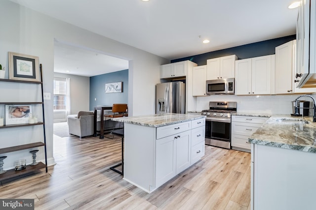 kitchen with white cabinetry, appliances with stainless steel finishes, a center island, and sink