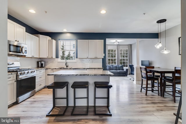 kitchen featuring sink, a breakfast bar area, white cabinetry, a center island, and appliances with stainless steel finishes