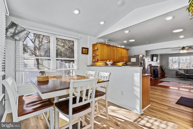 dining area with ceiling fan, lofted ceiling, and light hardwood / wood-style flooring