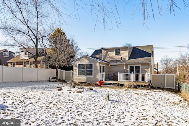 snow covered back of property with a wooden deck