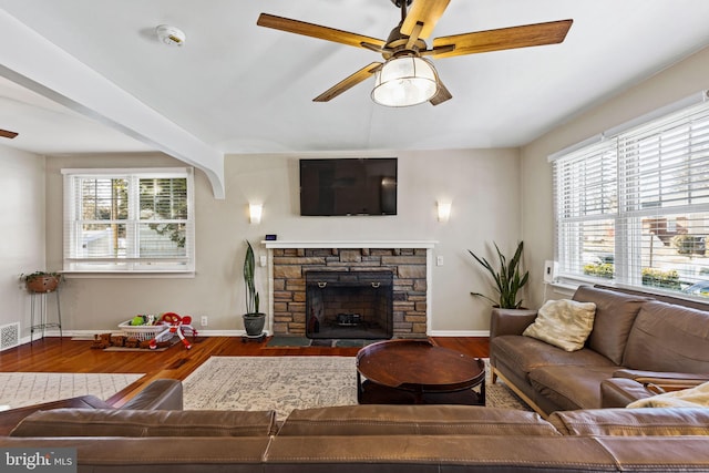 living room with ceiling fan, a stone fireplace, and hardwood / wood-style floors