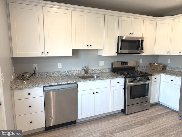 kitchen featuring white cabinetry, stainless steel appliances, sink, and light stone counters