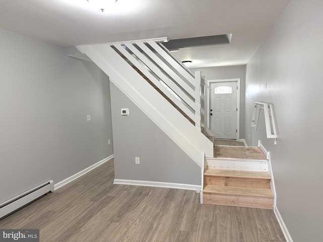 stairway featuring baseboard heating and hardwood / wood-style floors