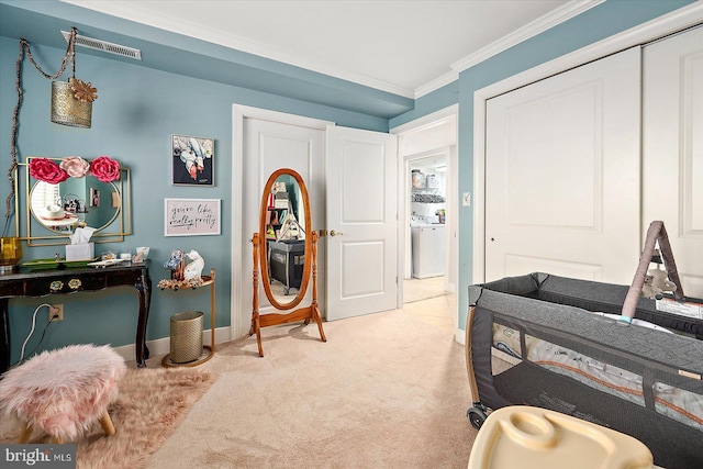 bedroom featuring ornamental molding, washer / dryer, light colored carpet, and a closet