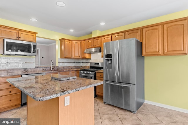 kitchen with tasteful backsplash, appliances with stainless steel finishes, a center island, and sink