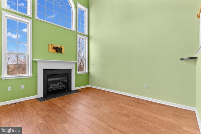 unfurnished living room with a towering ceiling and light wood-type flooring