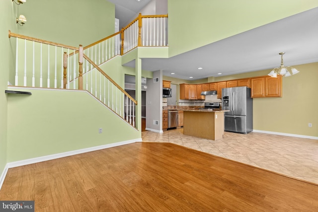 kitchen with decorative light fixtures, a chandelier, a center island, light hardwood / wood-style flooring, and stainless steel appliances