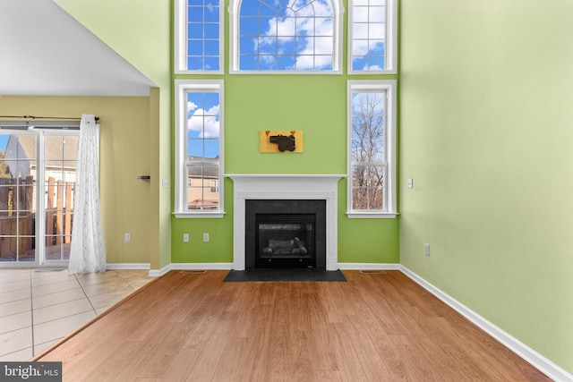 unfurnished living room featuring a towering ceiling and light hardwood / wood-style floors