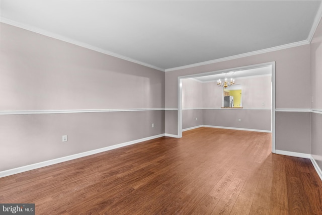 empty room featuring hardwood / wood-style floors, a notable chandelier, and ornamental molding