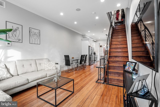 living room featuring crown molding and light hardwood / wood-style flooring